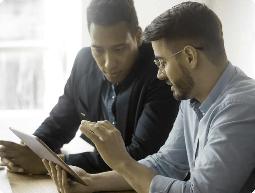 Zwei Entwickler arbeiten gemeinsam am Laptop mit eingeblendeten Codezeilen und Datenvisualisierungen für Software- und IoT-Analysen