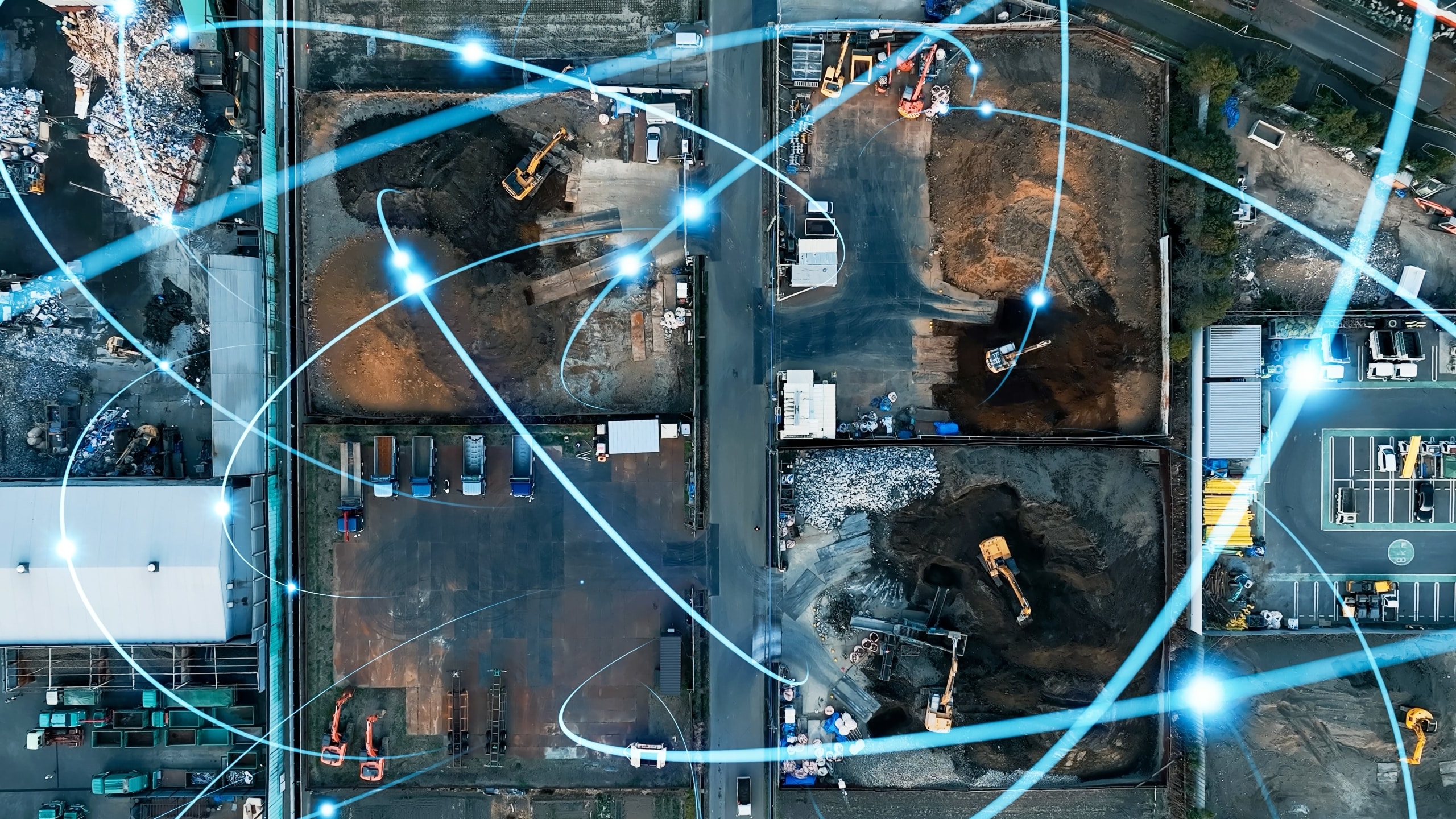 Luftaufnahme einer Baustelle mit mehreren Baufahrzeugen und überlagerten leuchtenden blauen Linien, die Vernetzung symbolisieren
